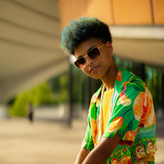 A pair of stylish aviator sunglasses with a reflective lens, resting on a wooden surface.